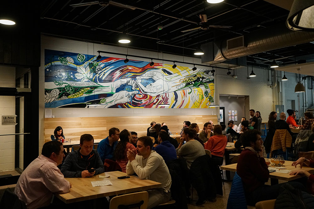 Full Room of People at Craft Brewery with Mural Art