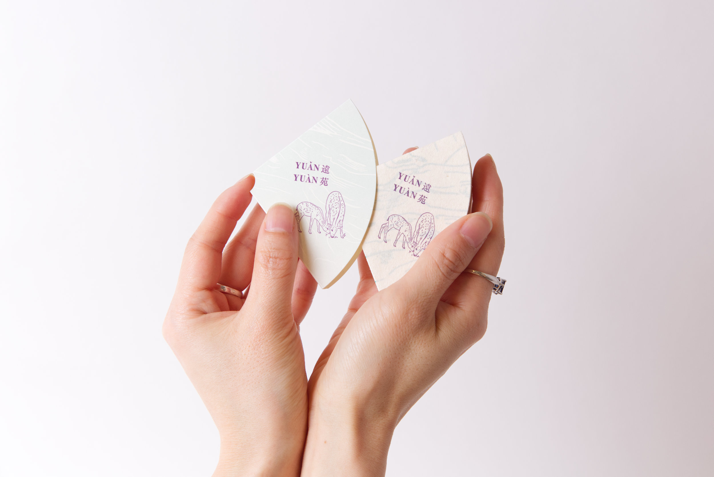 Artist's book fanned open resembling a flower, deep violet text visible through pages